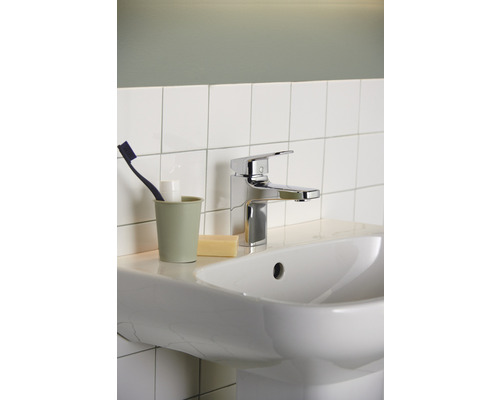 Waschbecken mit Armatur, Zahnbürste, Zahnputzbecher und Seife im Badezimmer