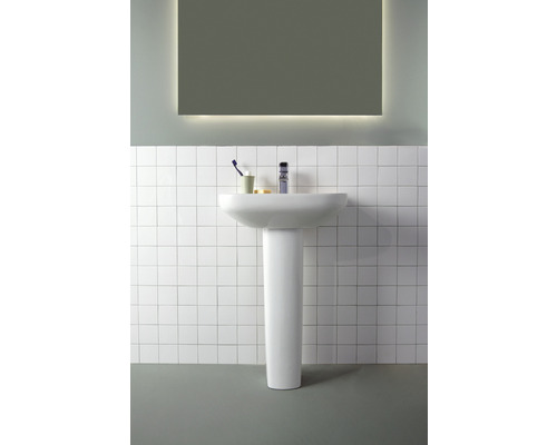Waschtisch mit Waschtischsäule in einem Badezimmer mit Spiegel