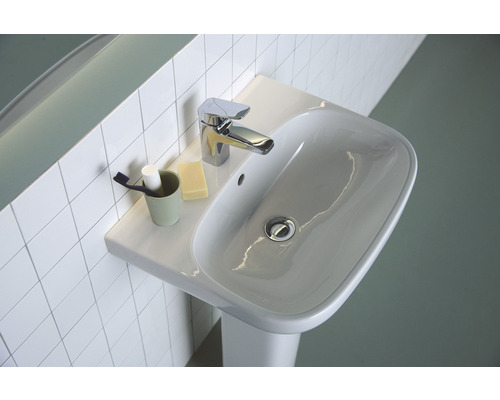 Waschbecken mit Armatur und Accessoires auf Ablage vor Fliesenwand