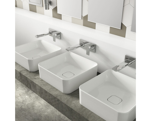 Drei quadratische Aufsatzwaschbecken aus Keramik mit Armaturen auf einer Betonplatte