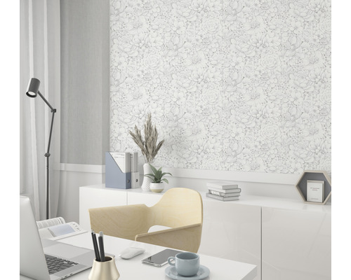 Büro mit Schreibtisch, Stuhl, Lampe und einer Wand mit floral gemusterter Tapete