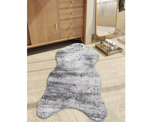 Dekoratives grauweißes Fellimitat vor einem Holzschrank und einem Spiegel