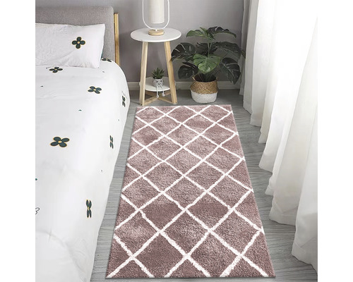 Schlafzimmer mit Bett, Beistelltisch, Topfpflanze und Teppich mit Rautenmuster