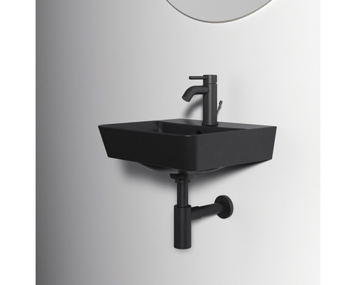 Schwarzes Aufsatzwaschbecken mit Armatur und Siphon vor einer Wand