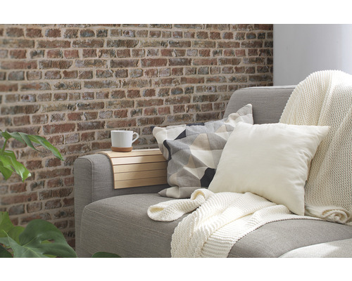 Wohnzimmer mit Sofa, Kissen, Decke und Wand in Backsteinoptik