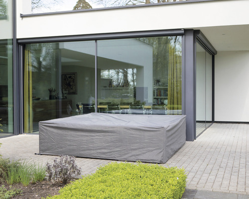 Abgedeckte Gartenmöbel auf einer Terrasse vor einem Haus