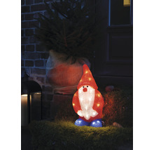 Dekorativer, beleuchteter Zwerg steht vor einem Hauseingang neben einem Weihnachtsbaum.