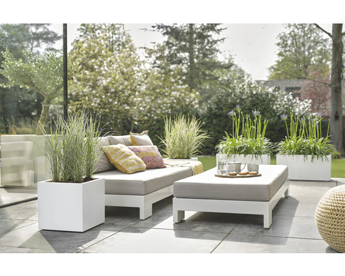 Szene mit Gartengarnitur, bestehend aus Sofa, Hocker und Pflanzenkübeln auf einer Terrasse