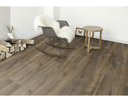 Innenraum mit Holzoptik-Bodenbelag, Schaukelstuhl mit Fell, Beistelltisch und Dekoration.