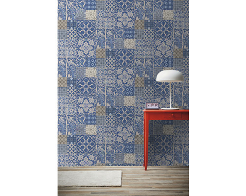 Raum mit gemusterter Tapete in Patchwork Optik, rotem Tisch und Lampe