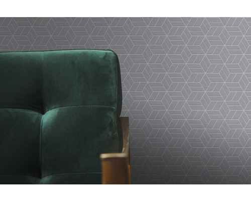 Nahaufnahme einer grauen Tapete mit geometrischem Muster und einem Teil eines grünen Sofas