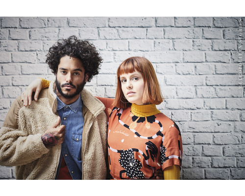 Porträt von zwei Personen vor einer Ziegelwand