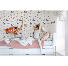 Zwei Mädchen sitzen auf einem Bett vor einer Wand mit Einhornmuster.