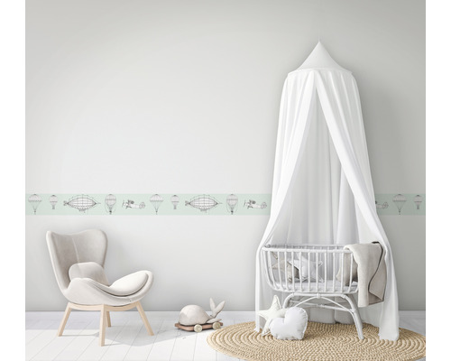 Kinderzimmer mit Wandbordüre, Sessel und Babybett