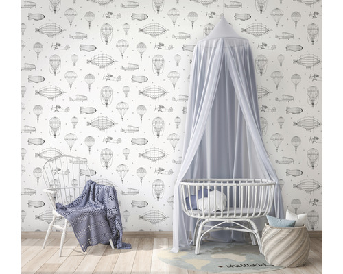 Zimmer mit Tapete mit Luftfahrtmotiven, Babybett mit Baldachin und Stuhl mit Decke