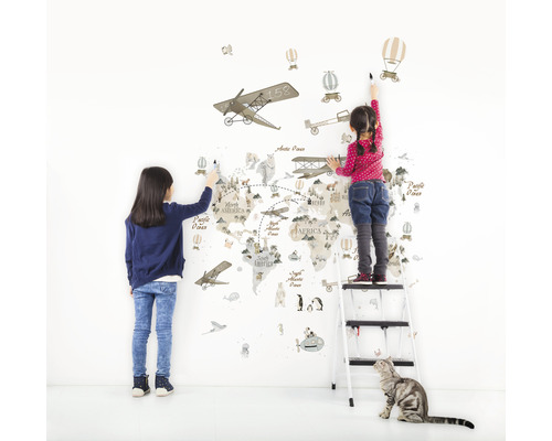 Zwei Kinder bemalen eine Weltkarte Wandaufkleber mit Flugzeug-, Heißluftballon- und Tiermotiven.