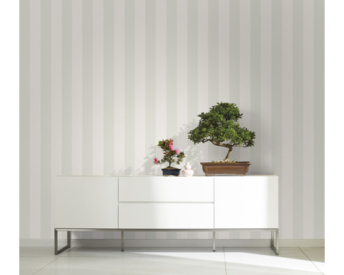 Raumansicht mit gestreifter Tapete, weißem Sideboard und Bonsai-Pflanzen als Dekoration