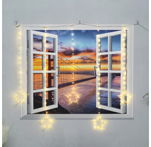 Dekoratives Fenster mit Lichterkette in Sternform und Blick auf eine Brücke bei Sonnenuntergang.