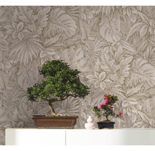 Zwei Bonsai-Bäume auf einem Schrank vor einer Wand mit Blättermuster-Tapete.