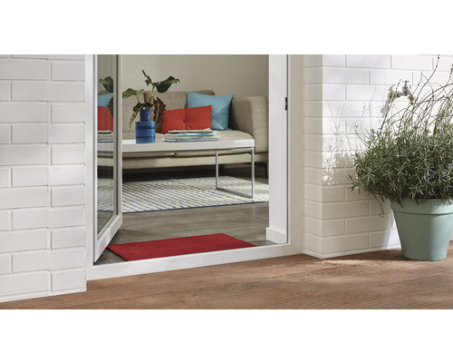 Szene mit Außenterrasse, Ziegelmauer, Pflanze im Topf und Blick in ein Wohnzimmer durch eine Terrassentür