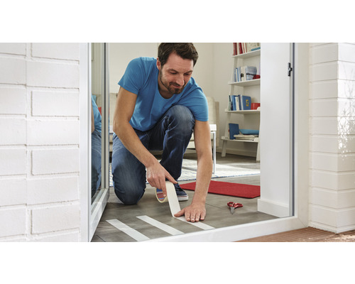 Mann klebt Abdeckband auf Fliesenboden