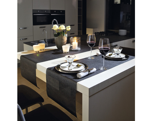 Esstisch mit Tischläufer, Gedecken, Weingläsern, Blumenvase und Kerzen in modernem Küchenambiente.