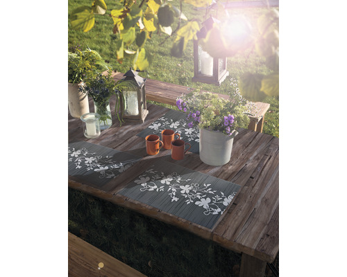 Gartentisch mit Tischsets, Tassen, Blumenarrangements und Laternen