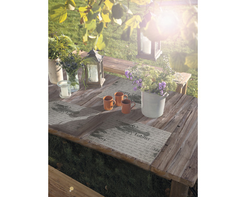 Gedeckter Holztisch im Garten mit Blumen, Windlichtern und Kerzen