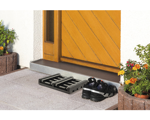 Fußmatte vor einer Haustür mit einem Paar Schuhen.