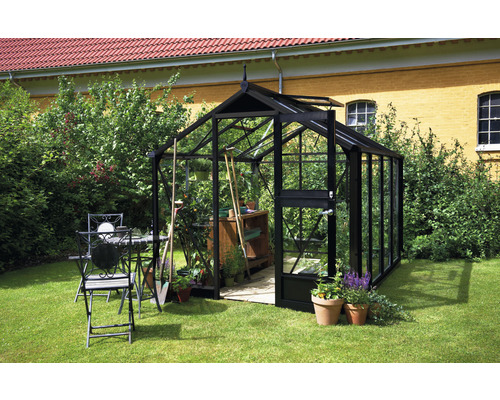 Gewächshaus mit Gartengeräten und Gartentischgruppe im Garten