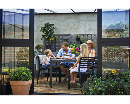 Familie sitzt in einem Gewächshaus am Tisch.