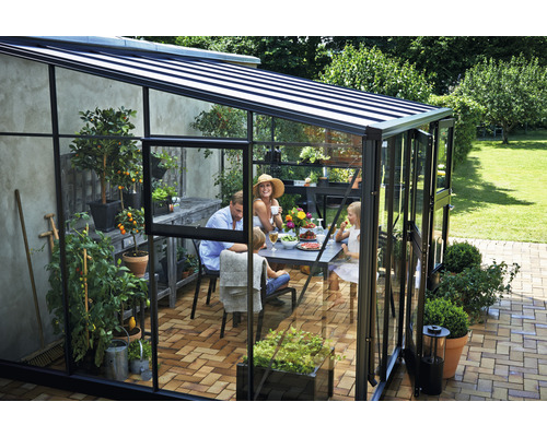 Gewächshaus mit Familie beim Essen im Garten