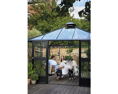 Gewächshaus mit transparenten Wänden und einer Gruppe von Personen am Tisch