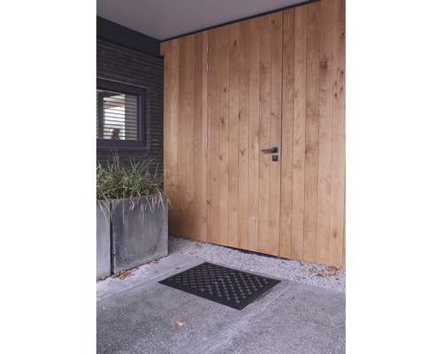 Eingangsbereich mit Holztür, Fußmatte und Pflanzenkübel