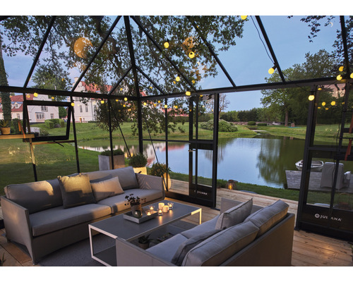 Gewächshaus mit Sitzgruppe und Blick auf einen See