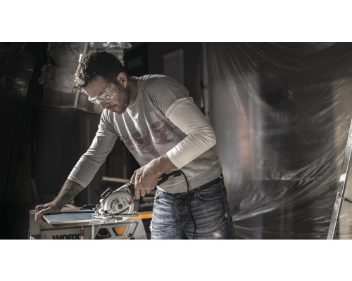 Mann mit Schutzbrille beim Schneiden eines Brettes mit einer Kreissäge von Worx