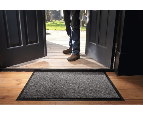 Fußmatte vor einer offenen Haustür auf einem Holzboden