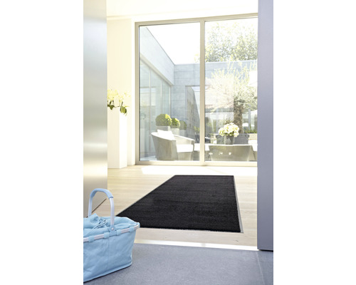 Eingangsbereich mit schwarzer Fußmatte und Wäschekorb
