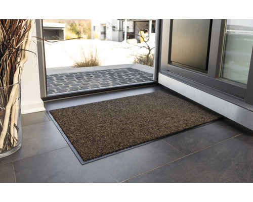 Fußmatte vor einer geöffneten Tür auf Fliesenboden