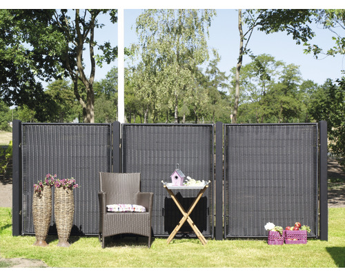 Gartenszene mit Sichtschutzzaun, Rattansessel und Gartentisch