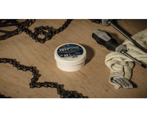 Dose mit Hochleistungsfett, Schraubendreher und Fahrradketten auf einem Holztisch