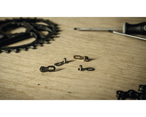 Fahrradkette, Kettenblatt und Schraubendreher auf einer Holzoberfläche