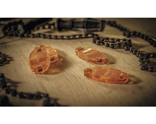 Fahrradspeichenreflektoren und Fahrradkette auf Holzhintergrund