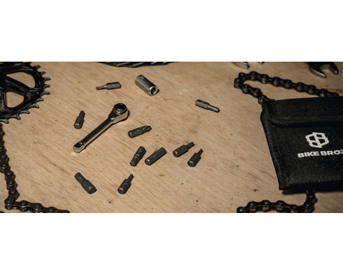 Fahrradwerkzeugsatz mit Ratsche, Bits, Kettenpeitsche und Bike Broz Tasche auf einem Holztisch