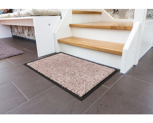 Schmutzfangmatte vor einer Treppe auf Fliesenboden.