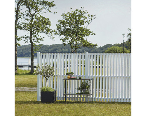 Gartenzaun aus Holz mit Pflanzen und Tisch im Garten
