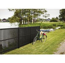 Dunkelbrauner Gartenzaun aus Holz neben einem See mit einem Fahrrad