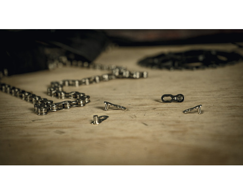 Fahrradkette mit Kettenschloss und Kettennieter auf einer Holzoberfläche