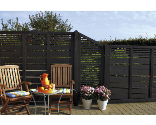 Gartenbereich mit Holzterrasse, Gartenmöbeln, Blumen und einem Zaun mit horizontalen Latten