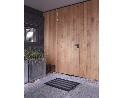 Eingangsbereich mit Holztür, Fußmatte und Pflanzkübel